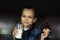 Little boy holds a bar of chocolate and glass of milk in his hands