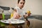 Little boy holds a paintbrush and picks up paint from the palette for coloring the Easter egg, which he holds in hand