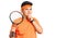 Little boy kid playing tennis holding racket serious face thinking about question with hand on chin, thoughtful about confusing