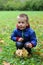 Little boy kneeling on the autumn meadow