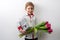 A little boy with a large bouquet of tulips and traces of kisses on his face on a white background.