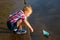 A little boy is launching paper boat in a river