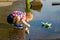 A little boy is launching paper boats in a river in the summer