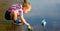 A little boy is launching paper boats in a river in the summer