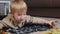 Little boy lays on floor and plays with toy dinosaurs at home