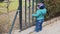 Little boy leans through door with metal bars. Caucasian child is trying to get out of closed yard. Freedom theme. Slow