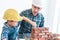 Little Boy learning to work on Brick wall and be a builder from his craftman father in vintage tone, Family working together on