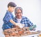 Little Boy learning to work on Brickwall and be a builder from his craftman father in vintage tone, Family working together on