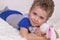 Little boy lies on a fluffy bedspread and hugs a teddy bunny