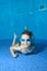 A little boy lies underwater at the bottom of the pool, looks at me and smiles widely. The view from under the water. Close-up