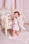 Little boy like angel smile and stand near luxurious armchair. Toddler boy in angel wings in baroque style interior room.