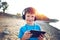 Little boy listening music on tablet in outdoor sunset