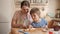 Little boy looking at mother cutting biscuits or sweet roll with jam filling. Children cooking with parents, little chef