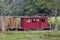 Little boy looks out the window of a red caboose train car