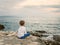 Little boy looks on the sunset sea landscape