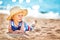 Little boy lying the beach in straw hat