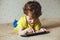 Little boy lying on bed and looking at tablet, using modern technology