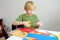 Little boy making colored paper crafts at home. Child cuts scissors details. Creativities lessons, distance learning,