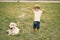 Little boy making a giant soap bubbles while playing with his dog on a grass