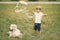 Little boy making a giant soap bubbles while playing with his dog on a grass