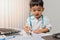 Little boy in medic uniform using a pen on desk