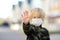 Little boy in medical face mask showing gesture Stop - keep social distance during coronavirus pandemic. Focus on palm. For safety
