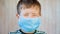Little Boy in a Medical Facemask Looking at the Camera Blinking and Smiling. Small Boy`s with Brown Eyes in Protective