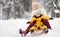 Little boy and mother/grandmother/nanny sliding in the Park during a snowfall