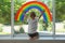 Little boy near rainbow painting on window, back view. Stay at home concept