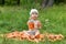 A little boy, one 1 year old, holding a jar of carrot juice on a pile of carrots in nature near a forest in a clearing and holds