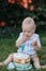 A little boy one 1 year old sits on the green grass in the garden and eats a sweet birthday cake, a funny smeared kid close-up top