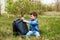 A little boy opens up his large backpack sitting on the grass
