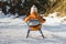 Little boy in an orange jumpsuit rides on a sled. Back view