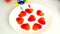 Little boy pierces candy in heart shape with stationery buttons of bright colors
