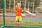 Little boy on playground with a grid of football gate