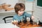 Little boy playing chess. Pupil kid thinking about his next move in a game of chess. Intelligent kids.