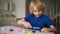 Little boy playing dough at home during coronavirus quarantine. Child molding from plasticine. Creativities lessons, distance lear