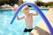 Little boy playing with floating noodle in kids pool during holidays with family in Greece