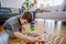 Little boy playing with montessori wooden toys in living room,mother and sister in backgroud.