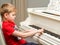 A little boy is playing the piano.