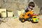 Little boy playing with toy digger and dumper truck.