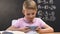Little boy playing video game on smartphone during school lesson, bad pupil