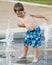 Little boy playing in a water fountain.