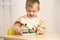 Little boy playing with wooden multicolored Montessori toys.