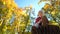 Little boy playing on wooden stump and waving hand at camera in autumn park