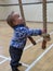 Little boy plays with climbing ropes and gazes upwards