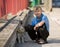 Little boy plays together with his puppy golden retriever dog outdoor at street, next to a red fence.