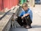 Little boy plays together with his puppy golden retriever dog outdoor at street, next to a red fence.