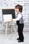 Little boy with pointer stands next to chalk board
