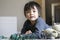 Little boy pointing finger on his nose and laying on the floor playing with soldiers and figurine toys in kid playroom, Active Kid